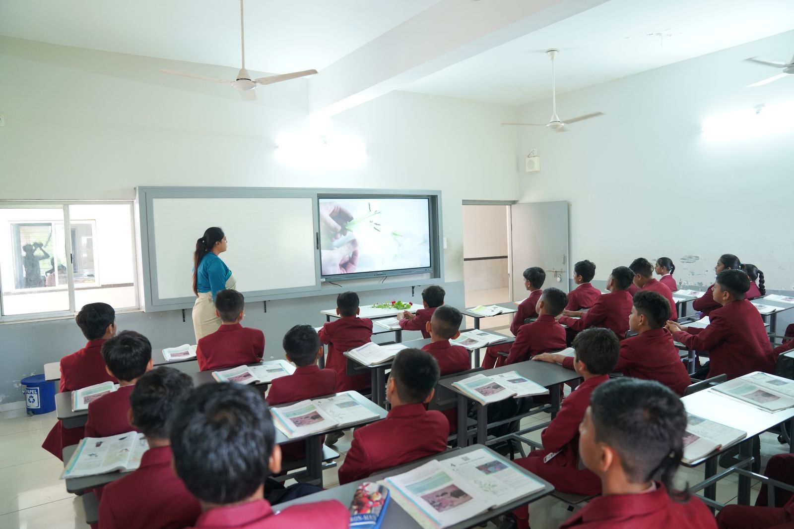 Students in maroon uniforms following a lesson on an interactive smart board in a bright classroom