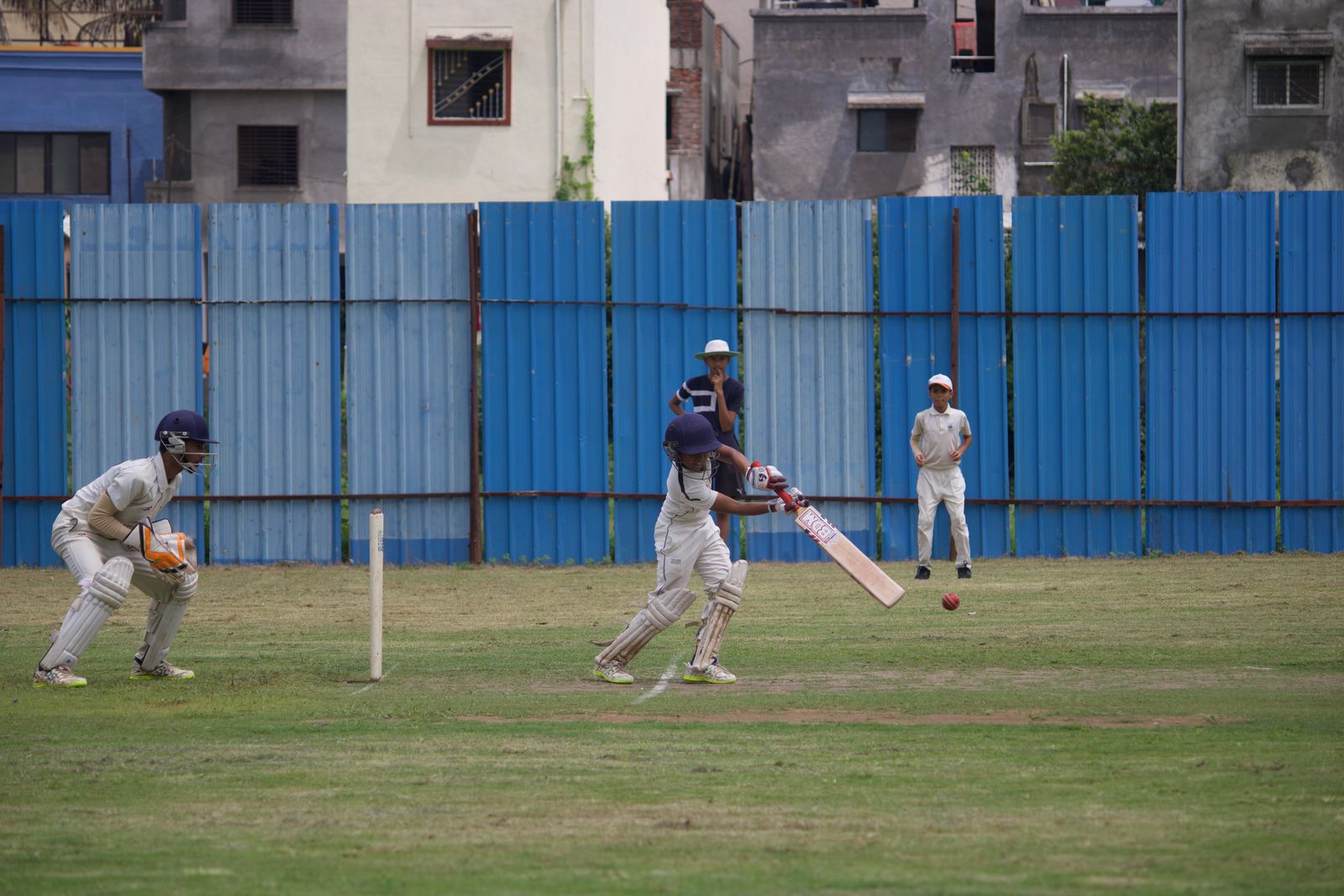 A young batter plays a shot during a cricket match on the school ground
